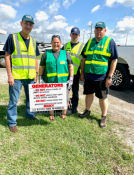 Four volunteers standing in front of a sign