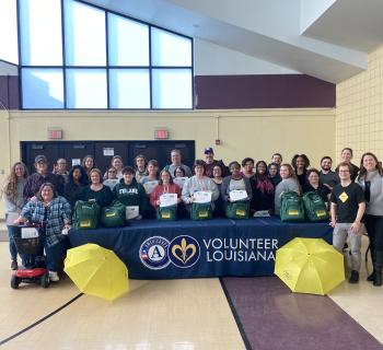 Louisiana Commission for the Deaf team standing and sitting behind a banner