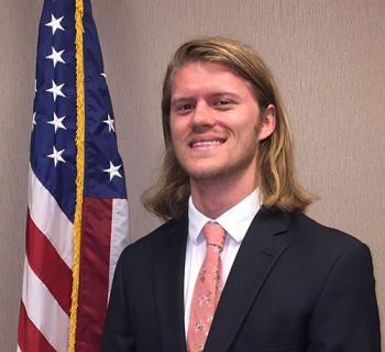 Matthew Fairbrother standing in front of the US Flag